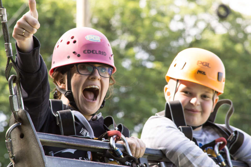 Two children hanging on a swing on an obstacle course