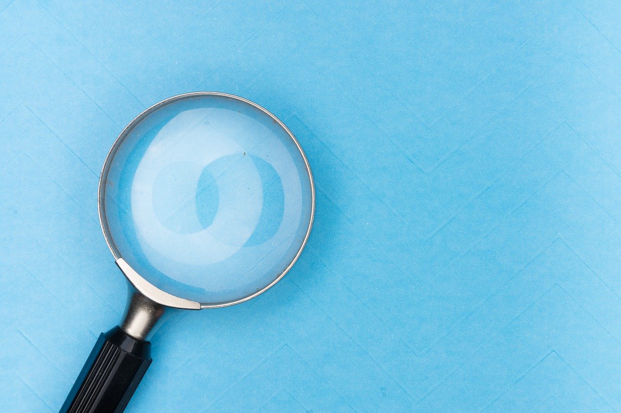 Magnifying glass looking at a blue background with the effect as though the magnifier is seeing paint