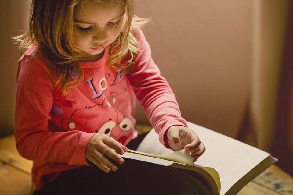 Toddler sitting reading a book