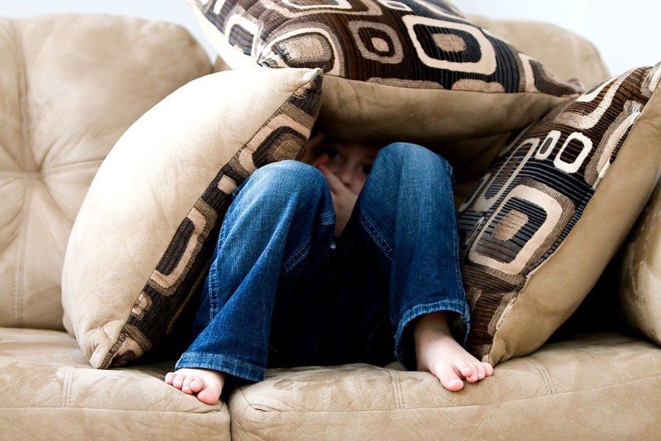 Boy hiding in cushions on the sofa