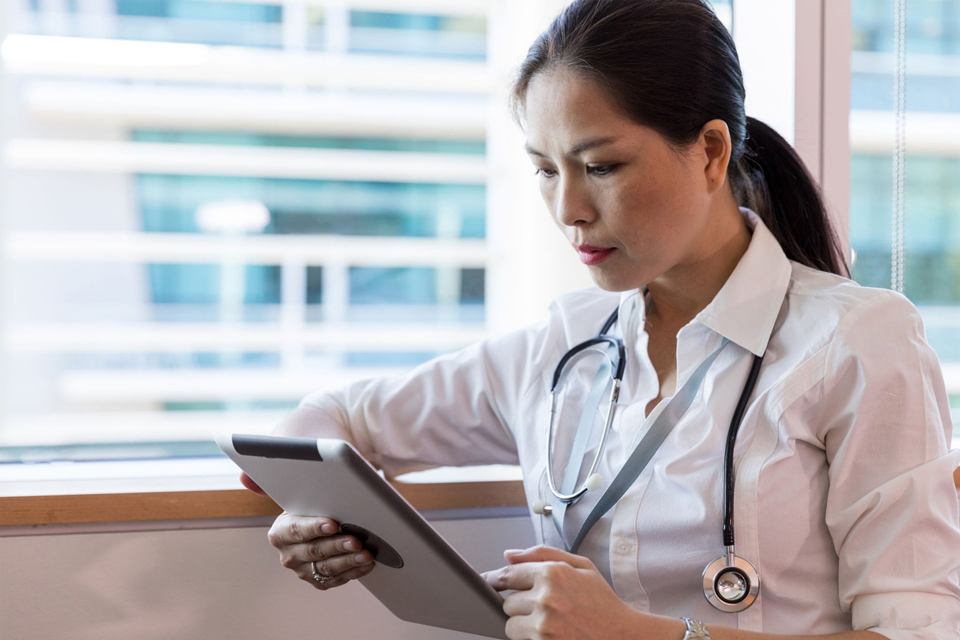 Photo of a female doctor studying a tablet computer
