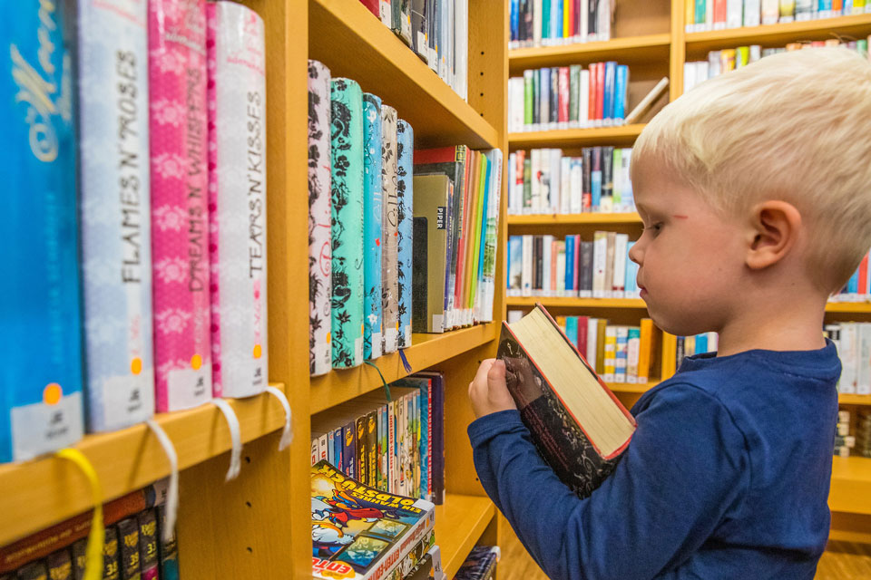 young child in a library looking at advanced books