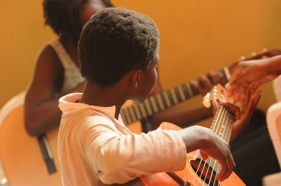 two primary school aged children learning to play guitar