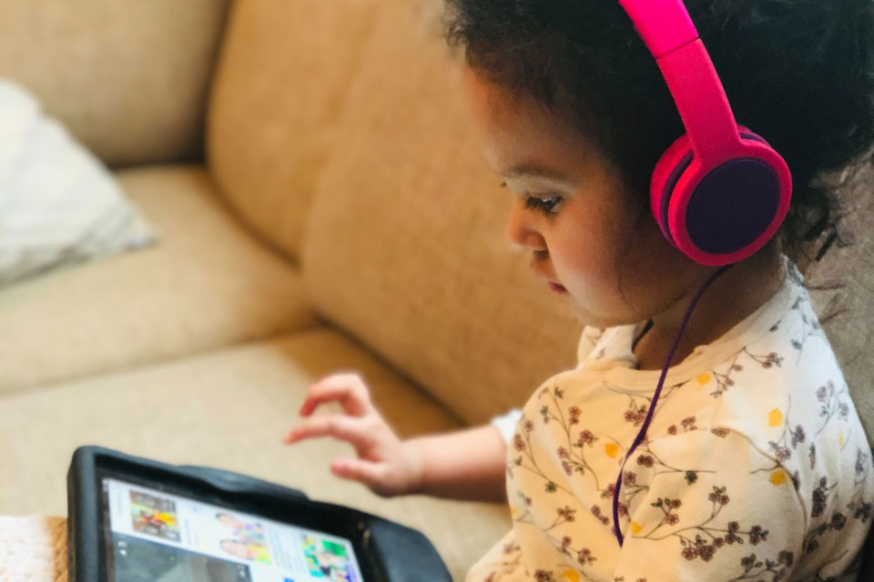 Young girl on sofa looking at a tablet, wearing headphones